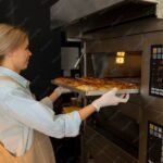 Boulangère au travail devant un four professionnel